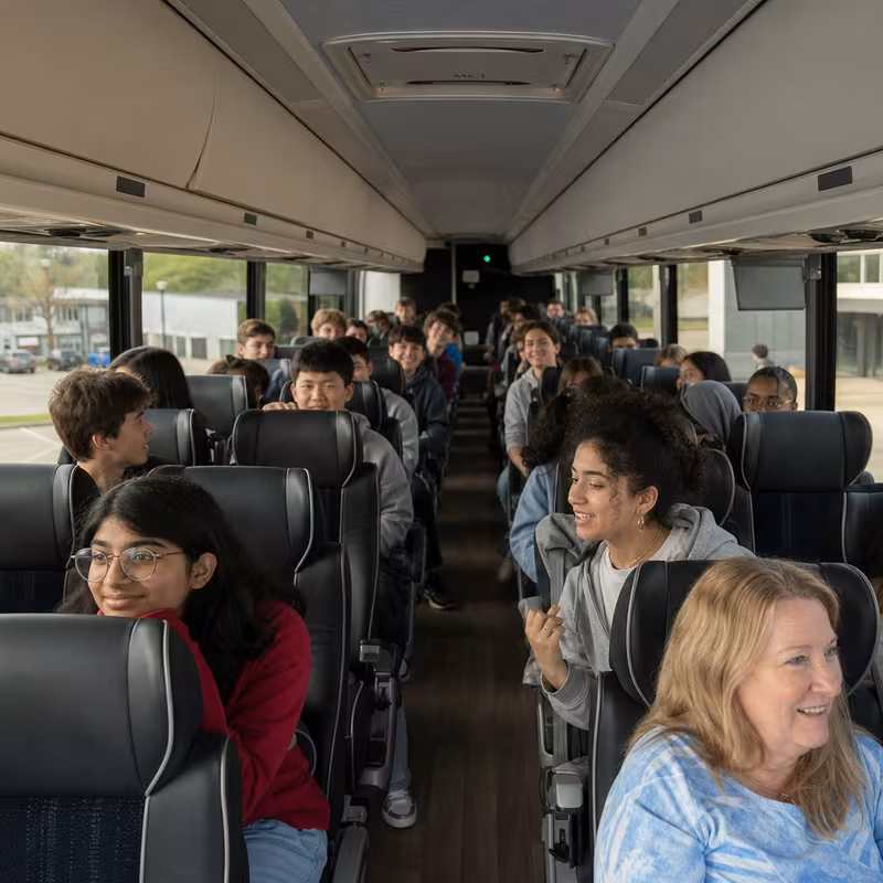Group boarding a white charter bus for School Transportation transportation in New Orleans